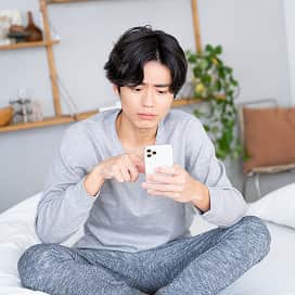スマートフォンを見て悩む男性